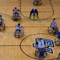 Adults wheeling in wheelchairs during a basketball game.